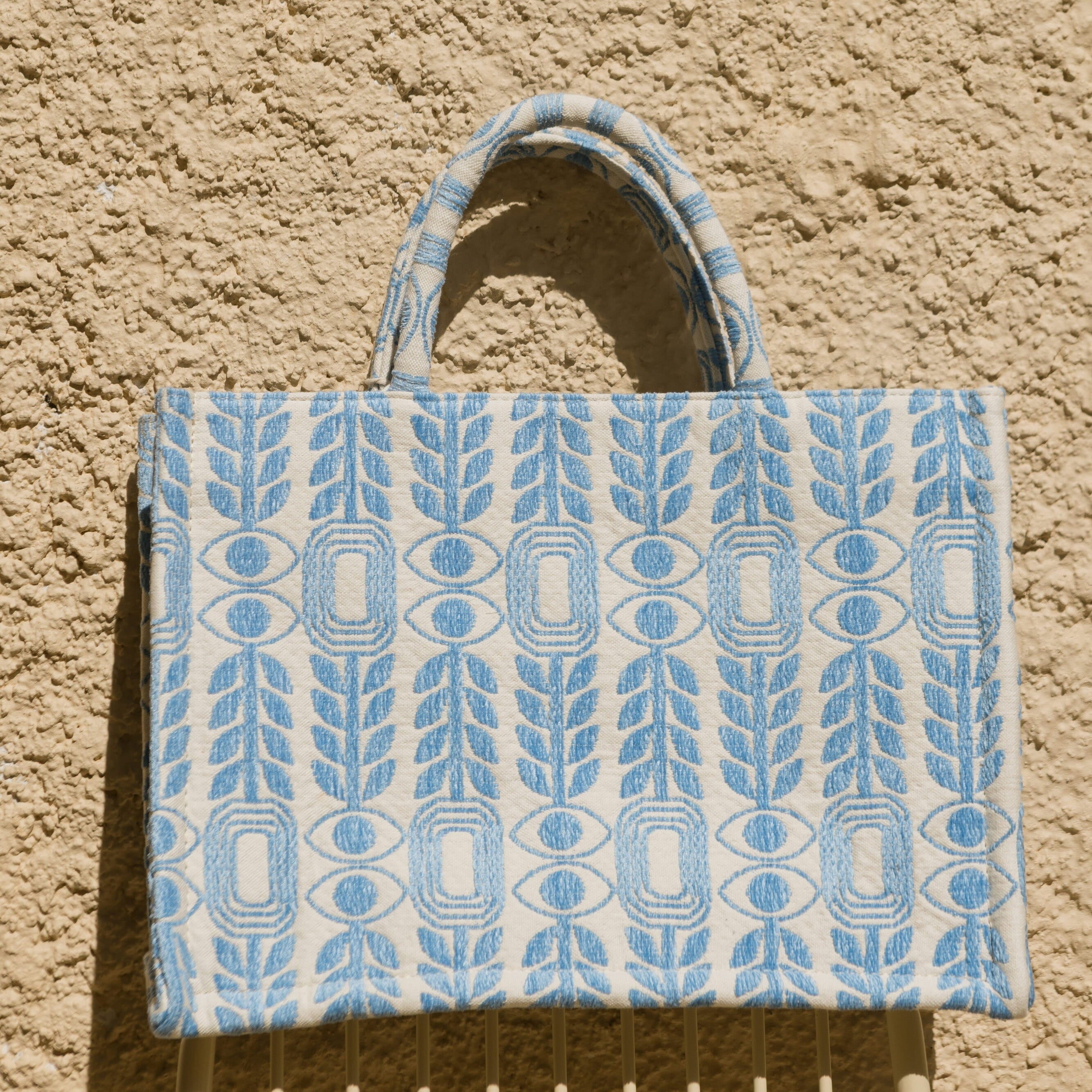 Marabu Unity Square Tote Bag flat lay — light blue evil eye embroidery on white natural cotton canvas, handmade in Greece
