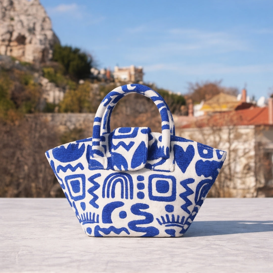 Marabu basket bag in blue Symbols print — natural cotton, dual handles, handmade in Greece, photographed against Greek landscape
