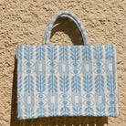 Marabu Unity Square Tote Bag flat lay — light blue evil eye embroidery on white natural cotton canvas, handmade in Greece