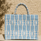 Marabu Unity Square Tote Bag front view — light blue Greek evil eye and olive branch pattern embroidered on natural cotton canvas